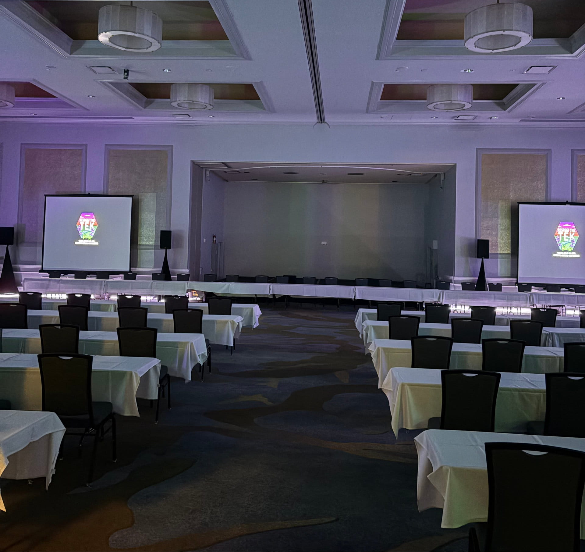 Professional line-array sound system and stage setup configured for a large corporate general session in a hotel ballroom.